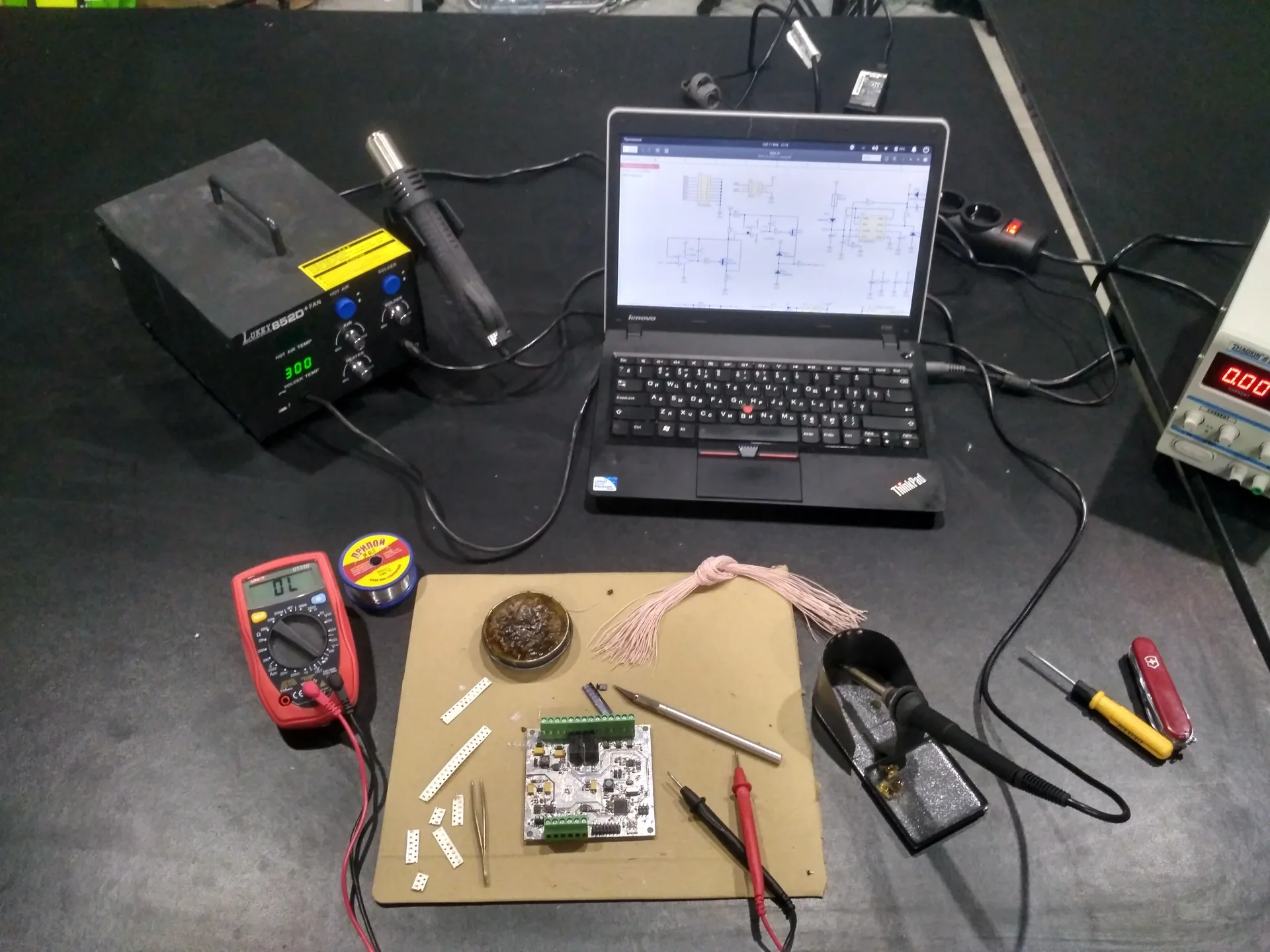 Electronics development workstation with a prototype board, schematic and test equipment.